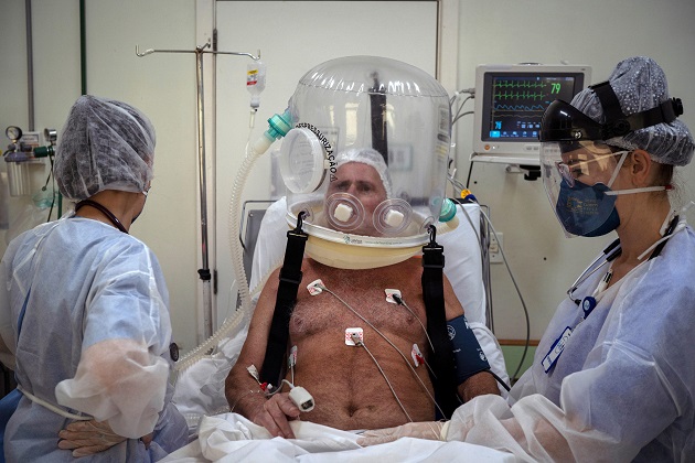 Trabajadores de la salud atienden con un casco burbuja a un paciente con la covid-19 en Brasil. Foto: EFE