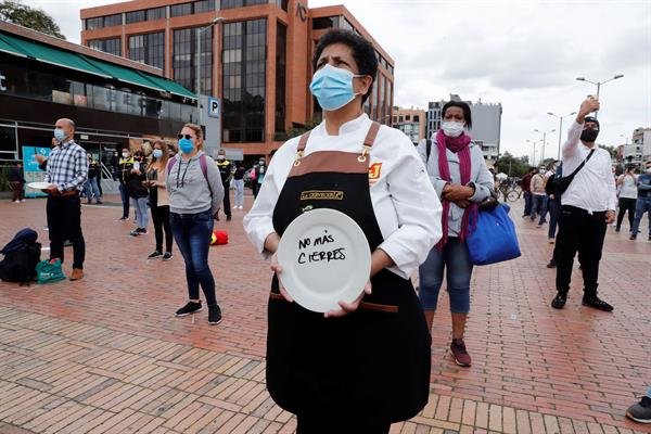 Una mujer sostiene un plato durante una protesta del gremio Asobares, hoy en Bogotá (Colombia).