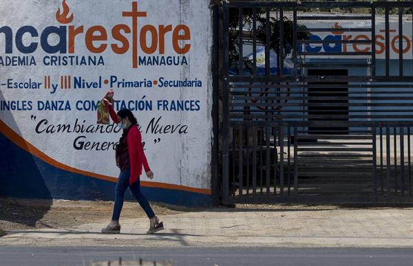 Un mujer camina frente a la puerta cerrada de una escuela hoy en Managua (Nicaragua). Foto: EFE