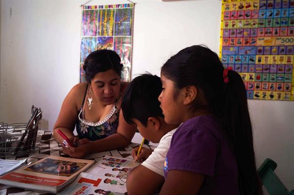 Una mujer acompaña a sus hijos en sus tareas.