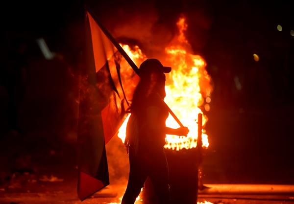 Fotografía del 3 de mayo de 2021 que muestra a un grupo de manifestantes que incendian llantas mientras bloquean vías durante las protestas en Cali (Colombia). Foto: EFE