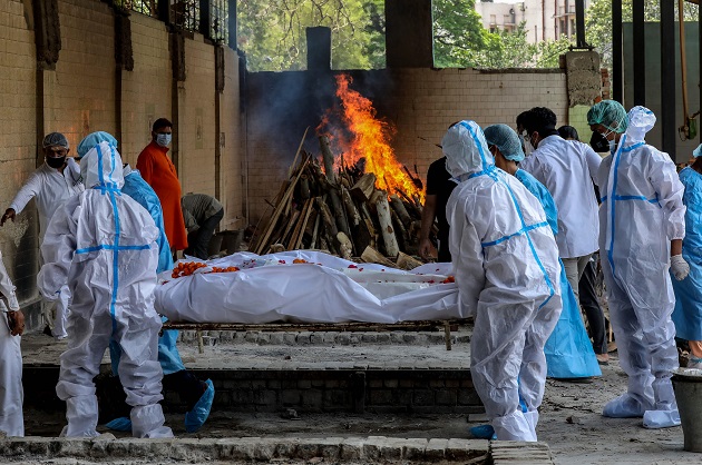 Las personas realizan los últimos ritos de una víctima de covid-19 en un campo de cremación en Nueva Delhi, India. Foto: EFE