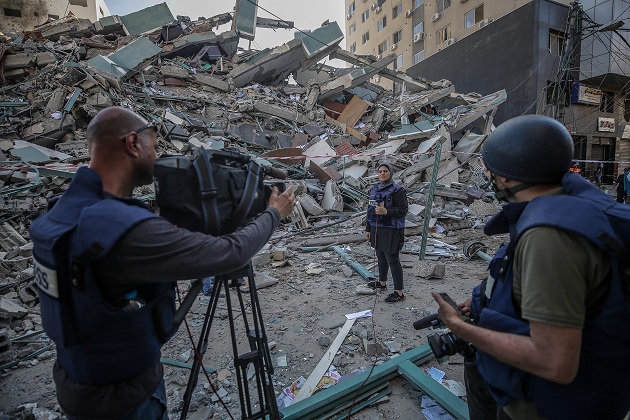 El equipo de televisión palestino trabaja junto a los escombros de su oficina destruida, la torre Al-Jalaa, que alberga apartamentos y varios medios de comunicación en la ciudad de Gaza. Foto: EFE