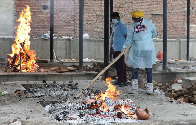 Voluntarios desinfectan durante un funeral masivo de víctimas de covid-19 en un crematorio en Nueva Delhi, India. Foto: EFE