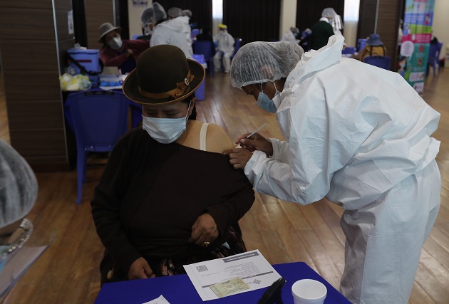 Una funcionaria de salud vacuna contra la covid-19 a una persona en la Escuela Militar de Ingeniería (EMI) en La Paz (Bolivia). Foto: EFE