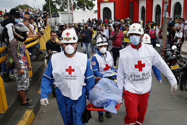 Miembros de la Cruz Roja Colombiana levantan el cuerpo sin vida de un hombre hoy, durante las manifestaciones en el sector La Luna, en Cali (Colombia).