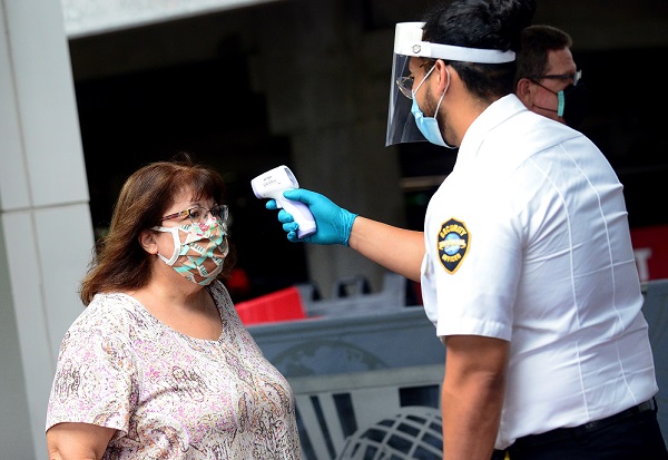 Un agente de seguridad de Universal Studios mide la temperatura a una señora que ingresa a dicho parque temático en Orlando, Florida (EE.UU).