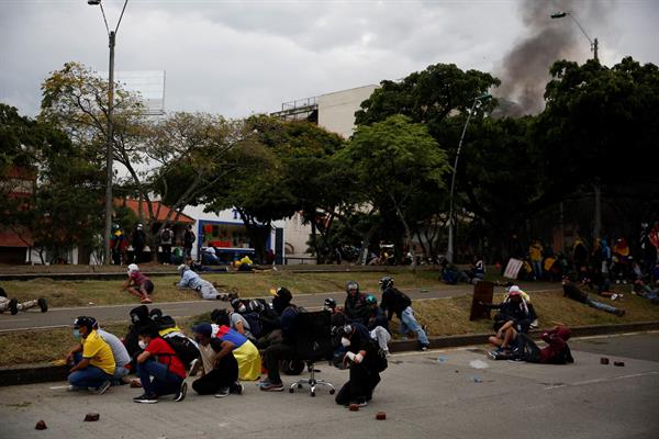 Manifestantes se cubren durante un enfrentamiento con la policía, en una jornada de protestas el 28 de mayo de 2021 en Cali (Colombia). EFE