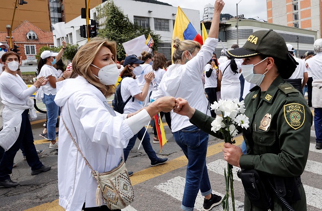 Una mujer y una policía se saludan hoy en Bogotá, Colombia, durante una marcha que rechaza y pide el fin del 