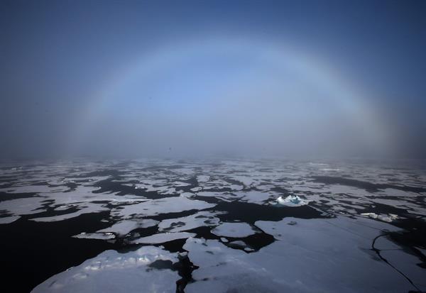 Un arco iris apareciendo en el horizonte en el Ártico.