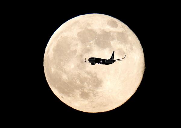 Un avión sobrevuela el cielo con la Luna de fondo. Foto: EFE