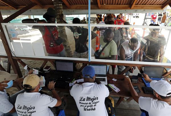 Fotografía tomada el pasado 3 de mayo en la que se registró a decenas de migrantes, de diversas partes del mundo, al comprar tiquetes para viajar a Capurganá, en el embarcadero de Necoclí (Colombia).