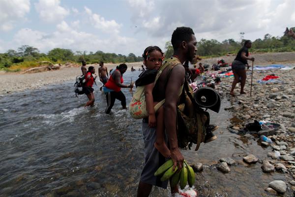 Migrantes caminan a través del río turquesa hacía la comunidad de Bajo Chiquito, tras caminar desde Colombia atravesando la selva del Darién (Panamá). Foto: EFE