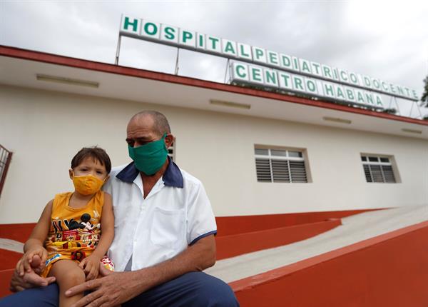 Un trabajador de la salud sostiene a un niño en sus piernas en la entrada de un hospital pediátrico hoy, en La Habana (Cuba). Foto: EFE