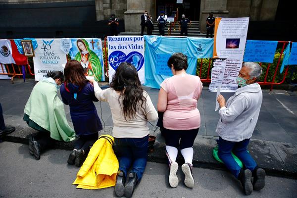 Un grupo de mujeres en contra del aborto rezan frente a carteles de protesta 