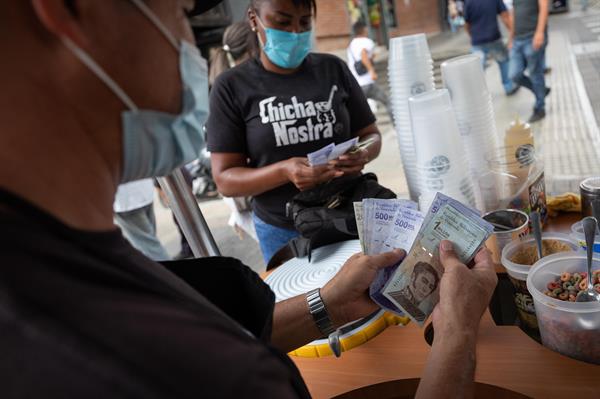 Vendedores cuentan billetes del antiguo cono monetario (Bolívar Soberano). EFE