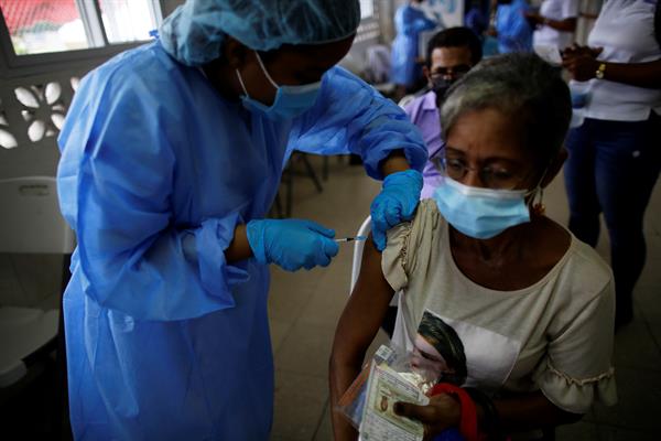 Personal médico mientras coloca la tercera dosis con la vacuna Pfizer en el centro de salud de El Chorrillo en Ciudad de Panamá.