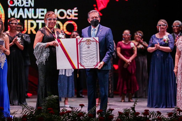 La docente Herminia Gómez Castillo, representante de la Escuela Oficial Bilingüe Simeón Conte, recibe el pergamino por parte del presidente Laurentino Cortizo. Foto: Cortesía Presidencia La docente Herminia Gómez Castillo, representante de la Escuela Oficial Bilingüe Simeón Conte, recibe el pergamino por parte del presidente Laurentino Cortizo. Foto: Cortesía Presidencia