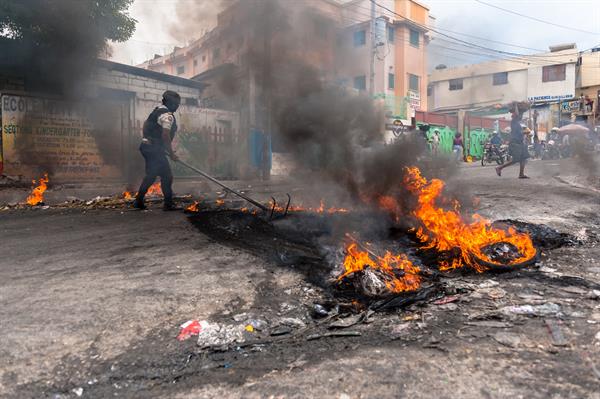 Un policía intenta disipar una barricada en llamas durante una jornada de protesta en Pétion-ville (Haití). EFE