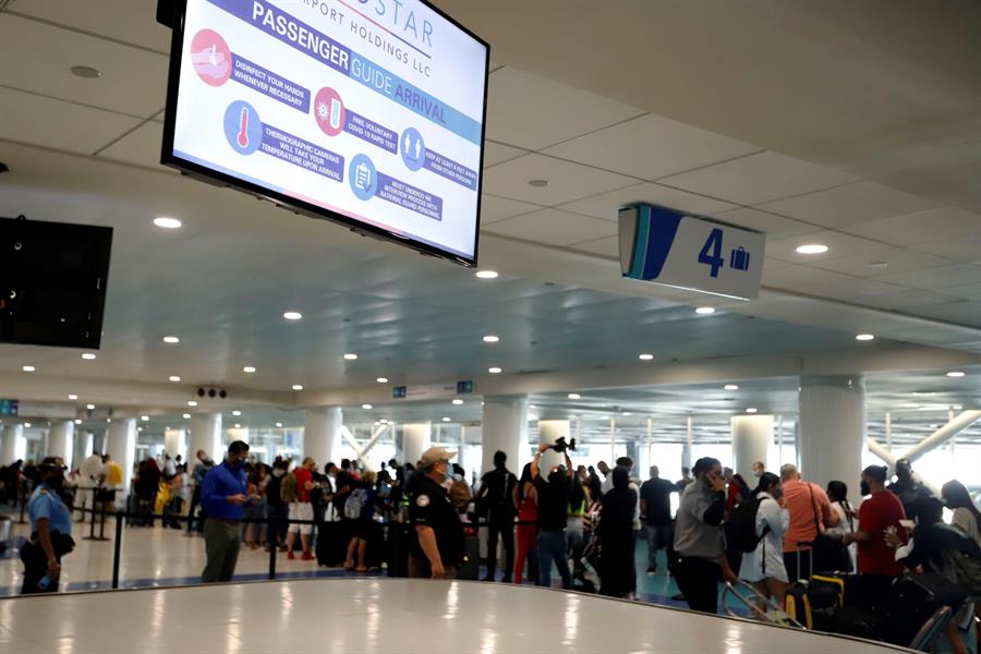 Pasajeros aguardan en cola para pasar las medidas de seguridad del covid-19 en el Aeropuerto Luis Muñoz Marín en San Juan.