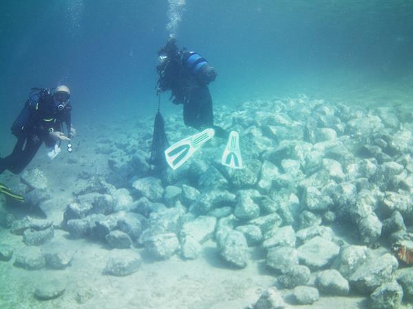 Imagen cedida por el Ministerio griego de Cultura de los arqueólogos examinando rocas en la parte sumergida del asentamiento prehistórico encontrado en Grecia.