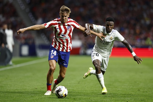 El centrocampista del Atlético de Madrid, Marcos Llorente (izq.), conduce el balón ante el delantero brasileño del Real Madrid, Vinicius Jr.. Foto:EFE