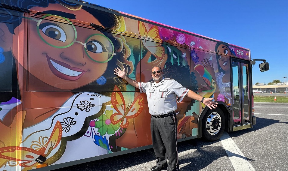 Conductor al lado de un autobús decorado con personajes de la película animada 'Encanto'. Foto: EFE/Disney
