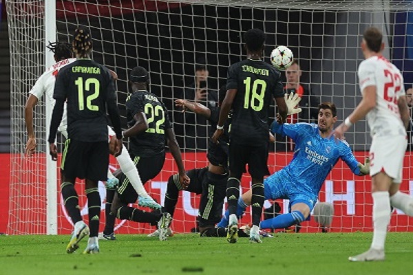 Christopher Nkunku del RB Leipzig ((izq.) anota el segundo gol de su equipo ante el marco del Real Madrid que protege el portero Thibaut Courtois. Foto: EFE