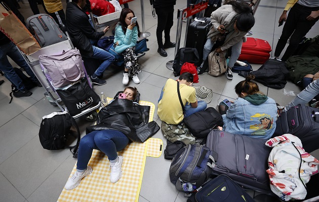 Centenares de personas sentadas en el suelo esperan repuestas. Foto: EFE