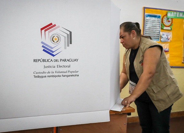 Una funcionaria acomoda una urna en una de las mesas electorales, en Asunción. Foto: EFE