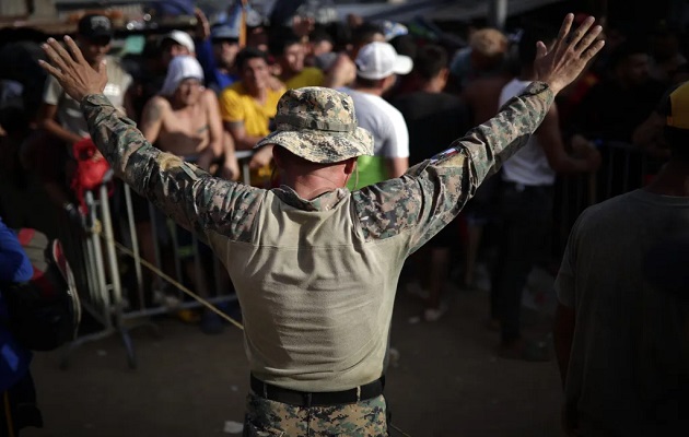 Un agente de Senafront controla a personas que esperan en fila para hacer su registro ante agentes de migración. Foto: EFE