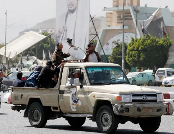 Simpatizantes hutíes viajan en un vehículo pasando junto a una pancarta que representa al máximo líder hutí, Abdul-Malik al-Houth. Foto: EFE