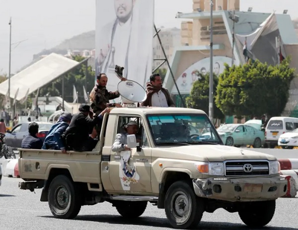 Simpatizantes hutíes viajan en un vehículo pasando junto a una pancarta que representa al máximo líder hutí, Abdul-Malik al-Houth. Foto: EFE