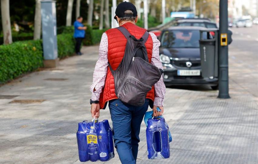 Un hombre carga con varias botellas de agua en Valencia. Foto: EFE