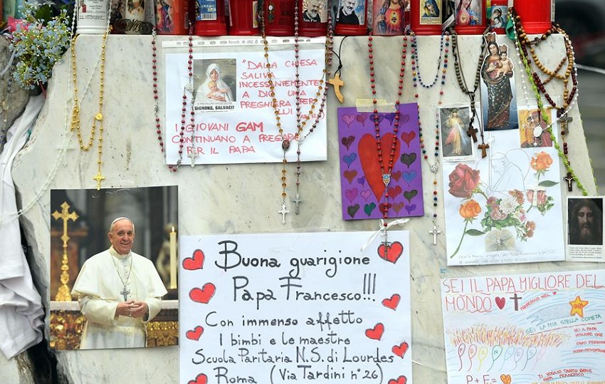 Velas, rosarios y mensajes de apoyo al papa Francisco se exhiben en la estatua del papa Juan Pablo II junto al Hospital Universitario Gemelli, donde está hospitalizado. Foto: EFE