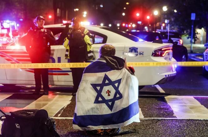 Un hombre con una bandera israelí, cerca del lugar donde dos personas fueron asesinadas. Foto: EFE