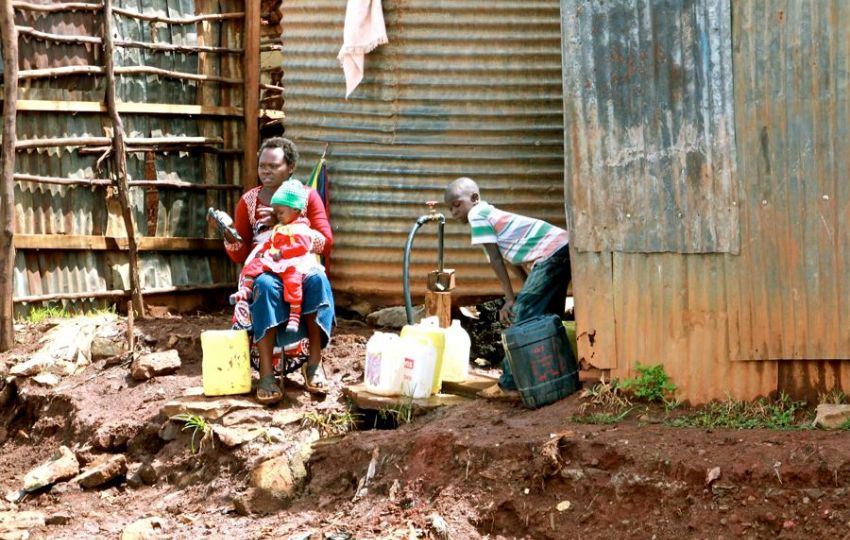 Una mujer y sus dos hijos recogen agua en bidones en uno de los distritos de Kibera (Kenia). Foto: EFE