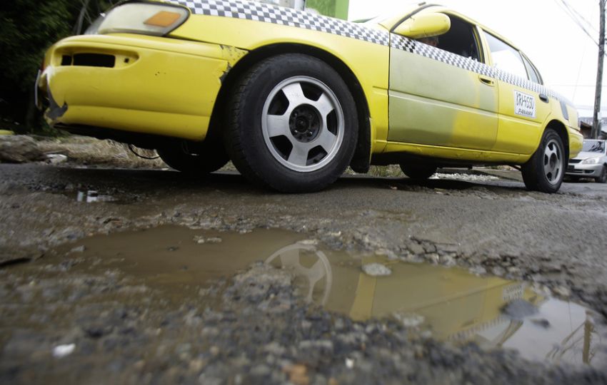 Vehículo pasa por una vía con huecos, en Ciudad de Panamá. Foto: EFE