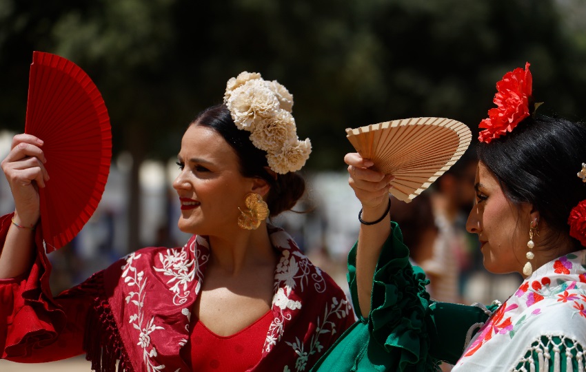 Varias mujeres vestidas de flamenca se cubren los ojos con abanico. Foto: EFE / Salas