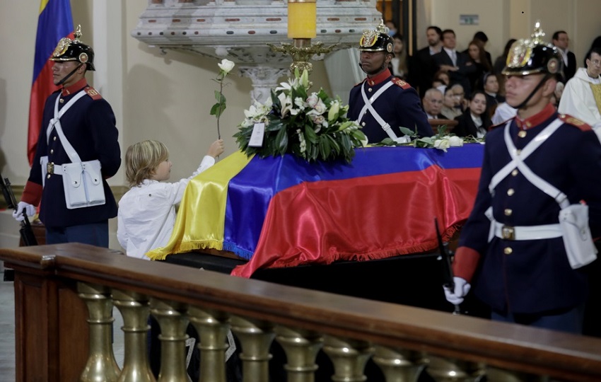 El hijo del fallecido senador y precandidato presidencial Miguel Uribe Turbay, Alejandro, lleva una flor frente el féretro. EFE