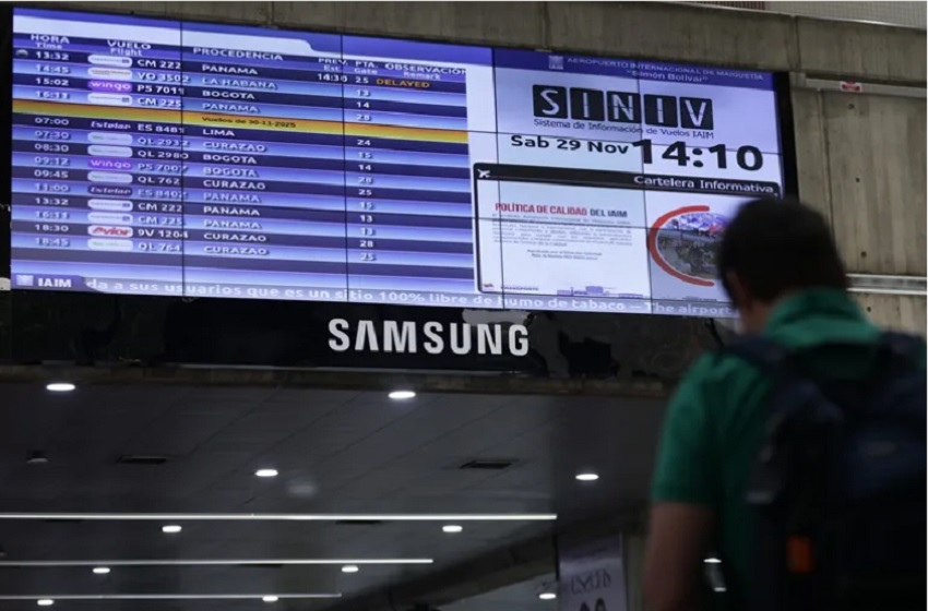 Fotografía de una persona caminando junto a una pantalla con la programación de vuelos, en el Aeropuerto Internacional Simón Bolívar, en Maiquetía (Venezuela). Foto: EFE/ Ronald Peña R.