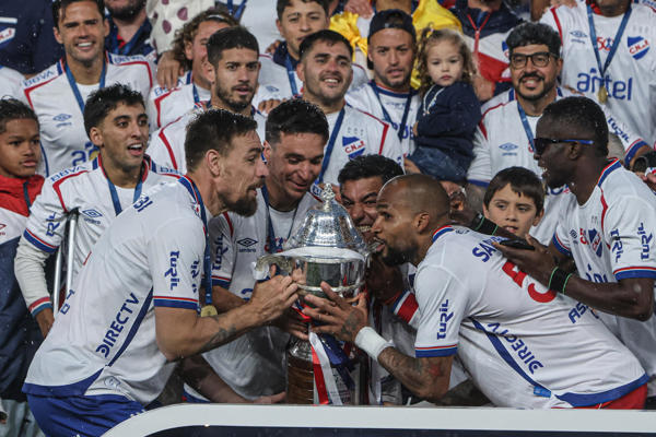 Luis 'Manotas' Mejìa (der.) levanta el trofeo de campeón en Uruguay.. Foto: EFE