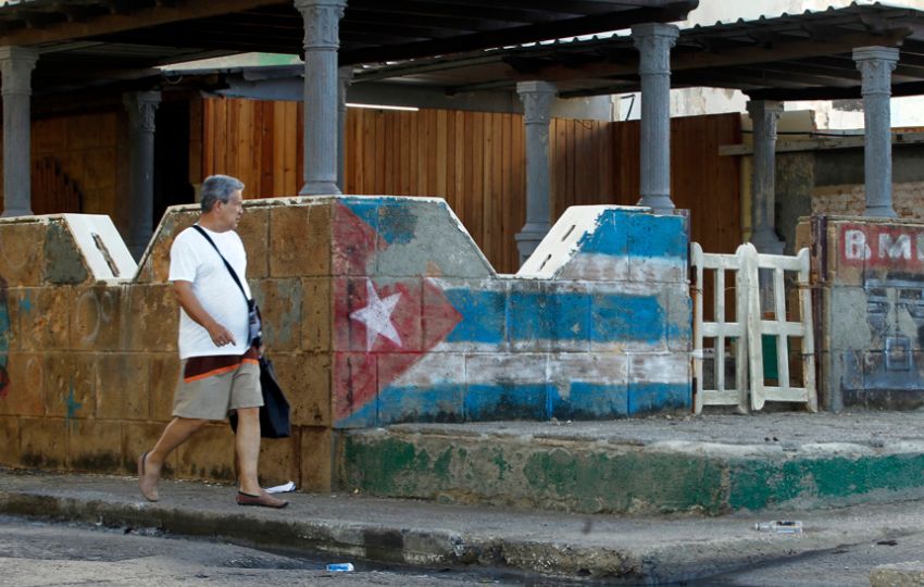 Un hombre camina junto a una pintura de la bandera cubana en La Habana (Cuba). Foto: EFE