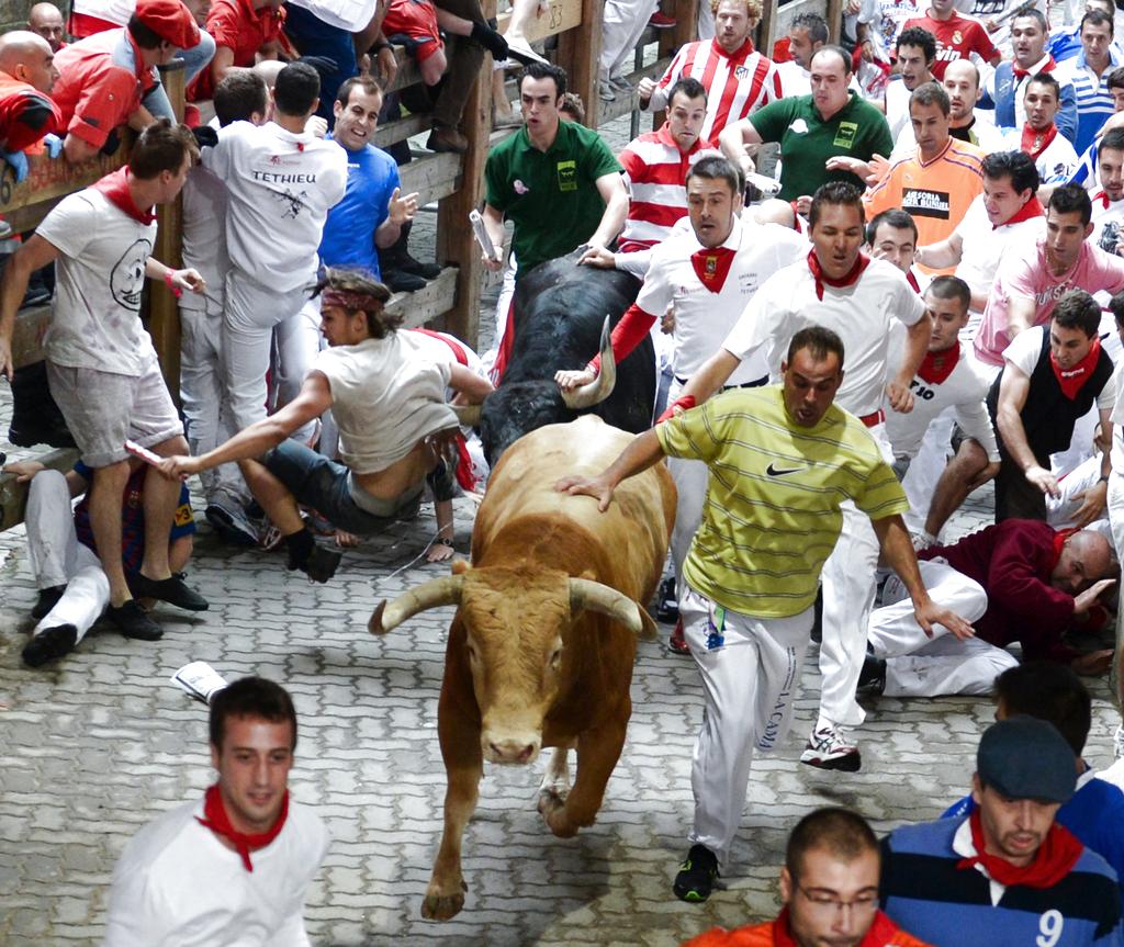 Un mozo es enganchado (i) por un toro: Foto: EFE<br>