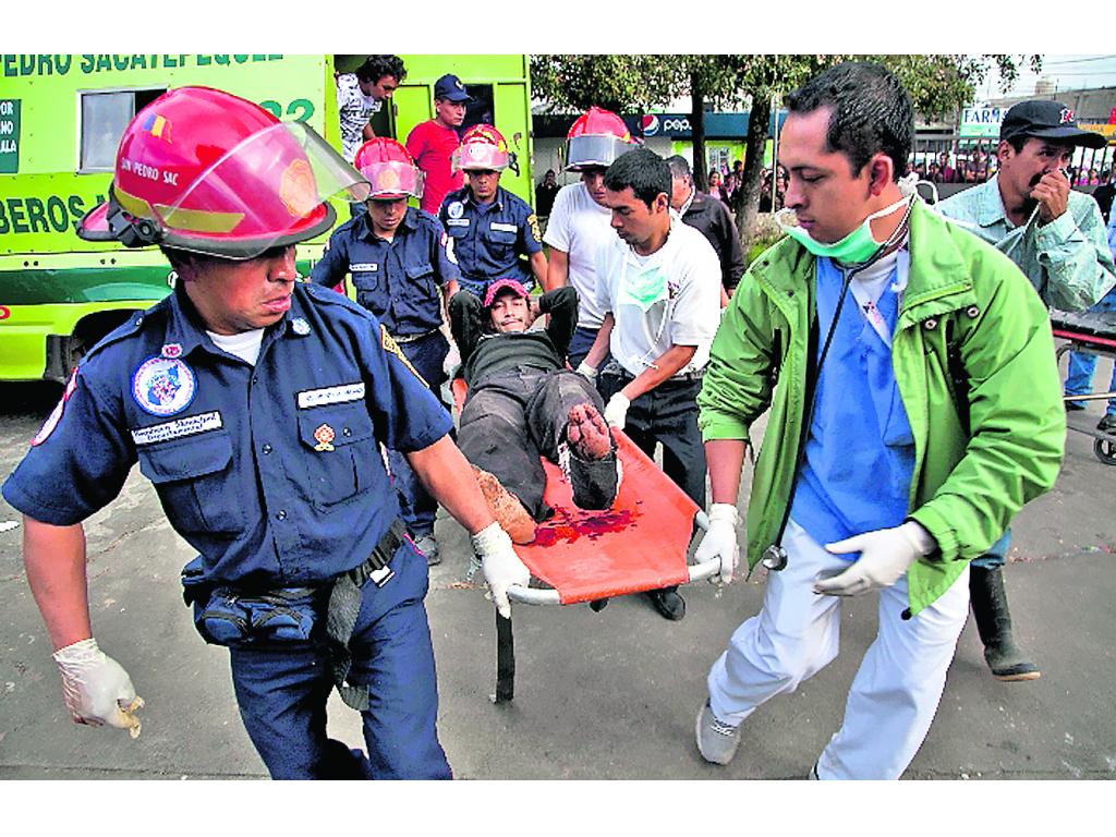 Dolor. Los bomberos transportan a un herido al hospital.(AP)