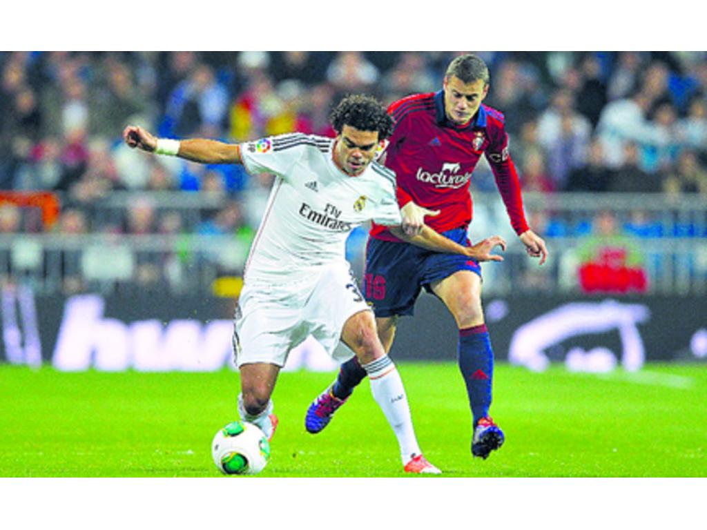 Pepe (izq.) protege el balón del jugador Oriol Riera, durante el encuentro de ayer.(AP)