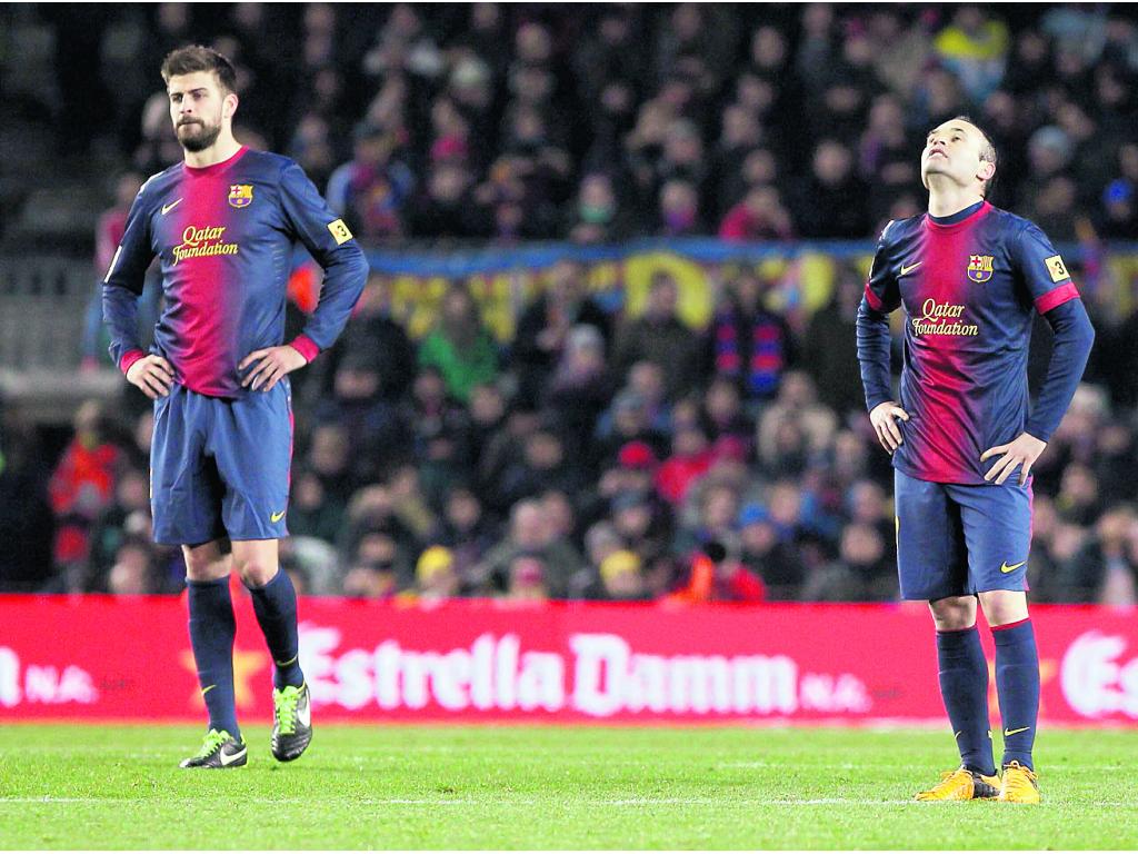 Piqué (izq.) e Iniesta no podían creer que estaban cayendo de manera aparatosa.(AP)