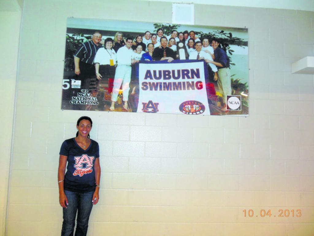 Eileen junto a la foto del equipo femenino de natación de Auburn que ganó el campeonato nacional de la NCAA en 2002.(Cortesía)