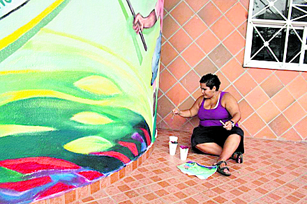Nadia Cerrud, retocando los colores de la mesa que es parte del mural. Al final se aprecia sobre la mesa el chicheme, un producto alimenticio que identifica a este sector de la provincia de Panamá.