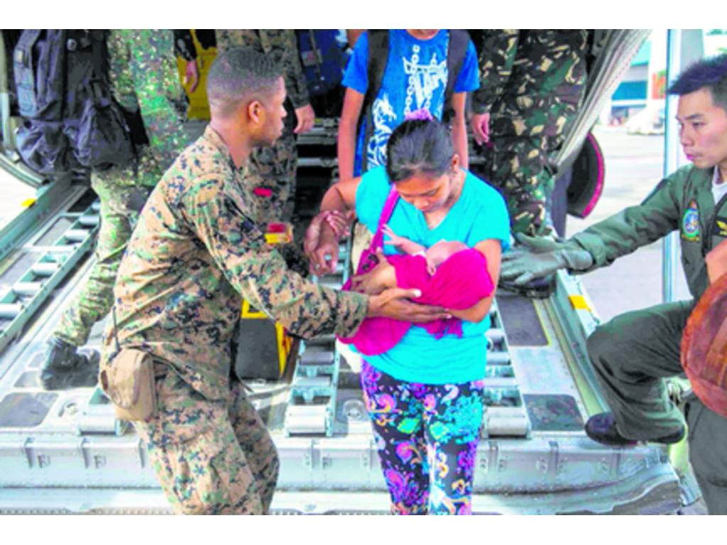 Una joven y su recién nacido salen de Tacloban.(AP)